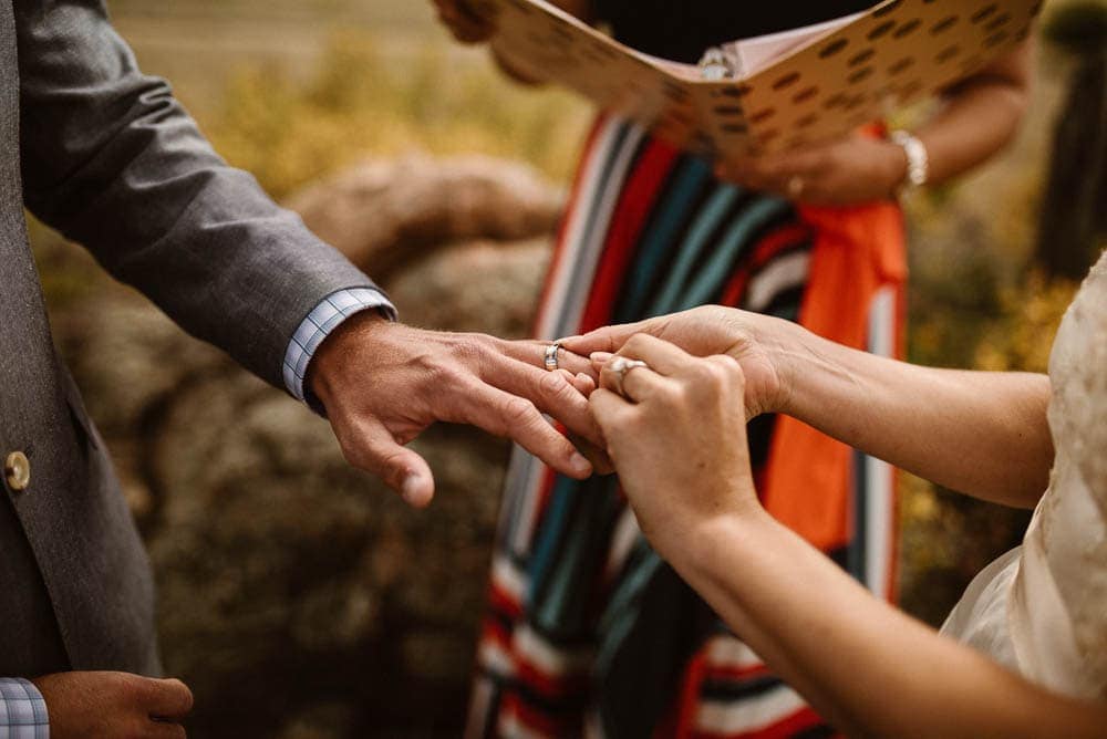Bride places ring on groom's finger during intimate elopement ceremony. 