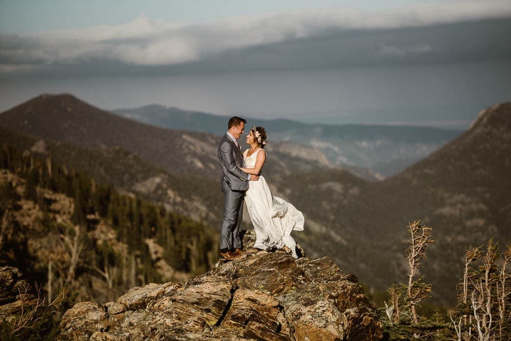 Bride and groom embrace, with mountains behind them, in Rocky Mountain National Park. 
