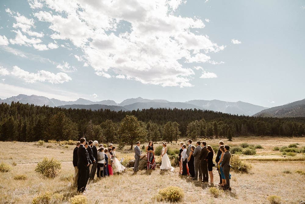 Bride, groom, their friends and family gather for an intimate sunrise elopement ceremony in Rocky Mountain National Park, Colorado. 