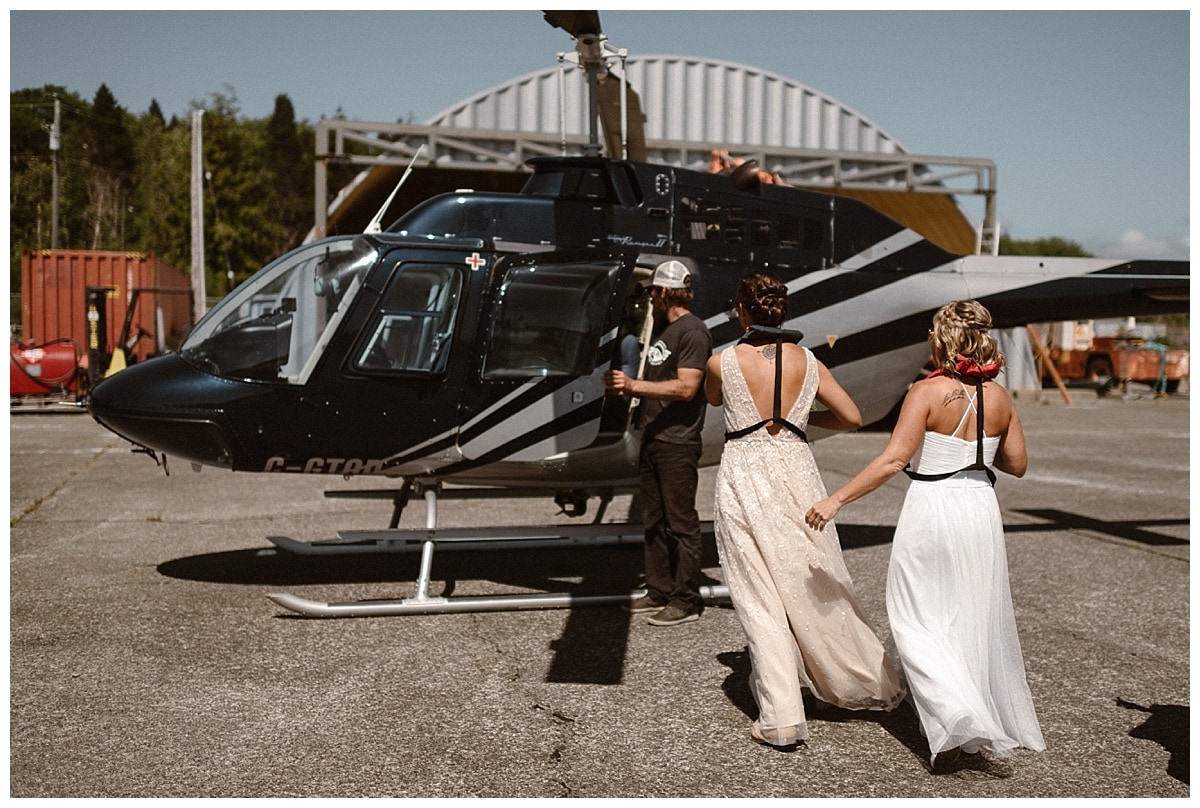 Two brides walk towards helicopter on their elopement day in Tofino, Canada. 