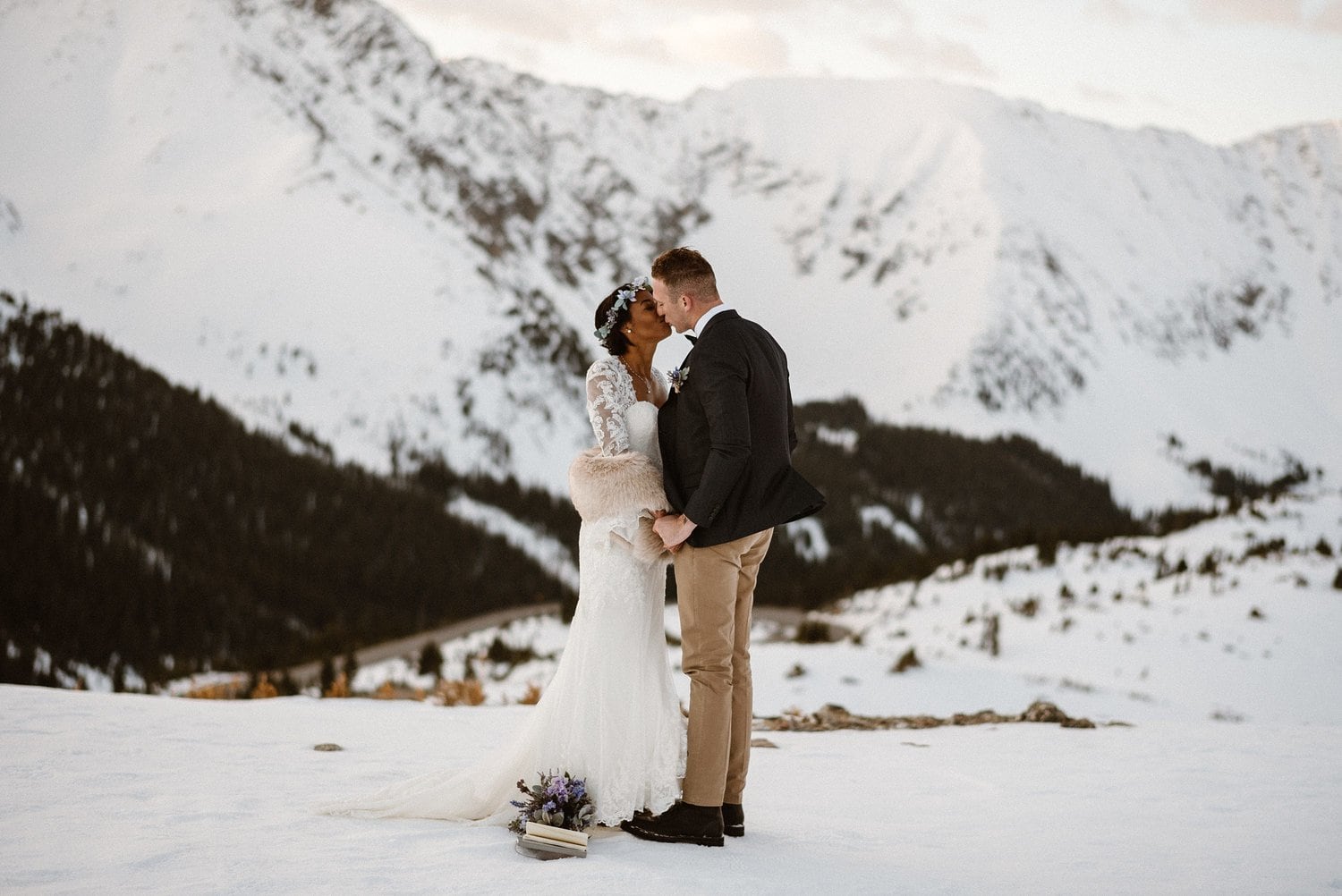 Bride and groom kiss during intimate elopement ceremony at Loveland Pass, in Colorado.