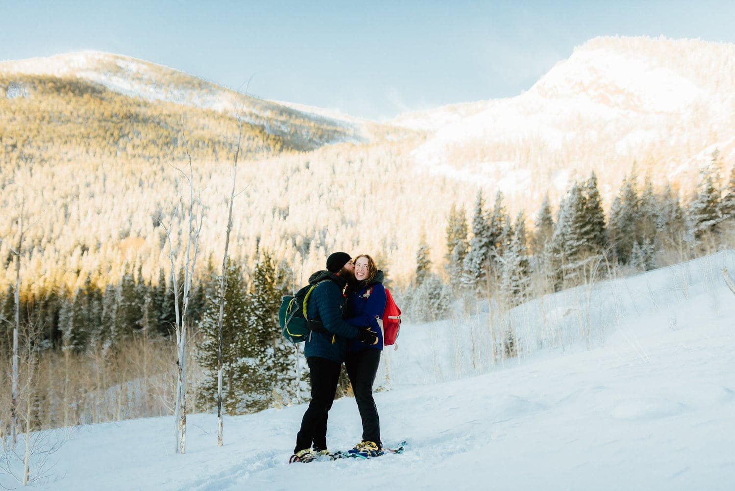 Couple embraces, while one partner kisses the other on the cheek at Indian Peaks, in Colorado. 