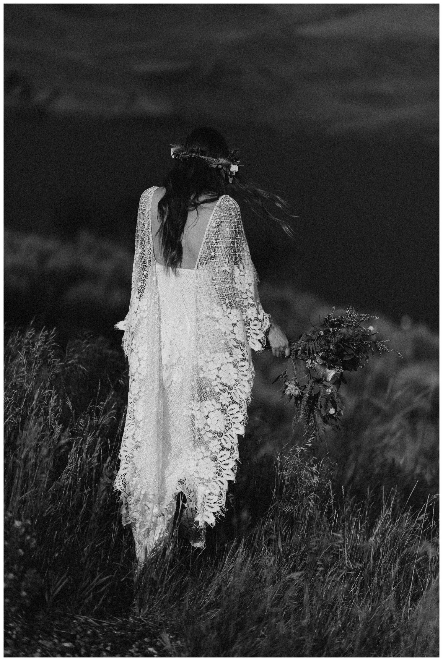 Bride walking in a grassy meadow, wearing a white dress, flower crown, and holding a bouquet.  