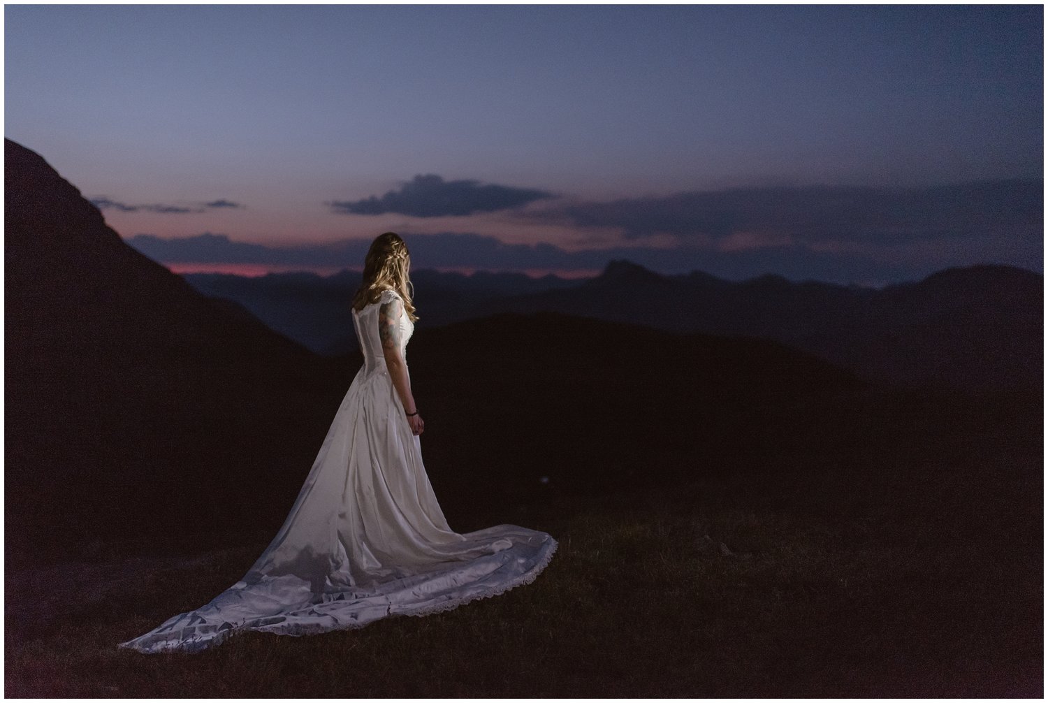 Bride looks out at mountain landscape as the sun rises in Ouray, Colorado. 