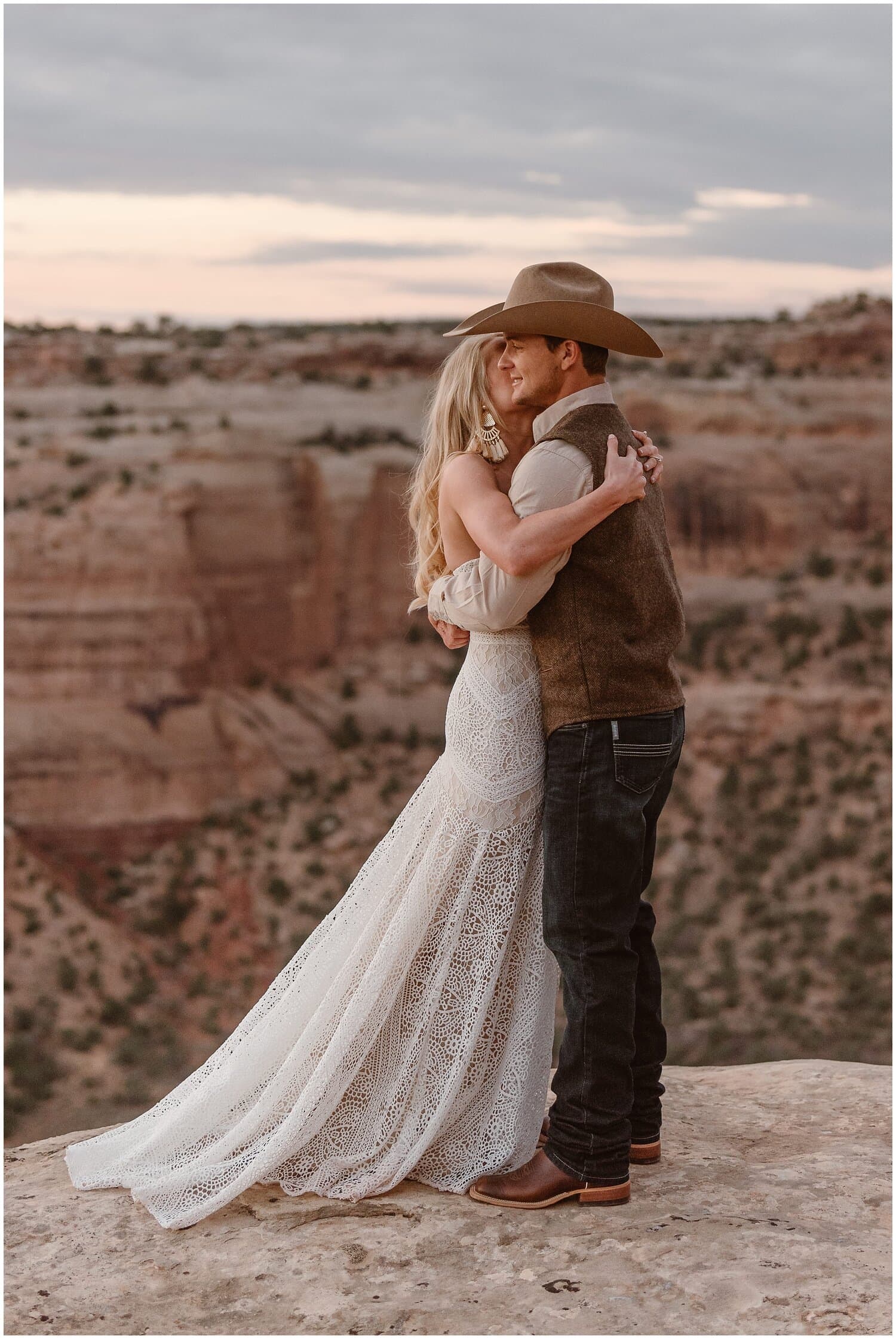 Bride and groom sit and look at landscape at Colorado National Monument. 