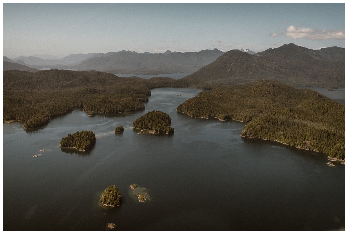 Aerial landscape of lake, islands, and tree-covered mountains in Tofino, Canada.