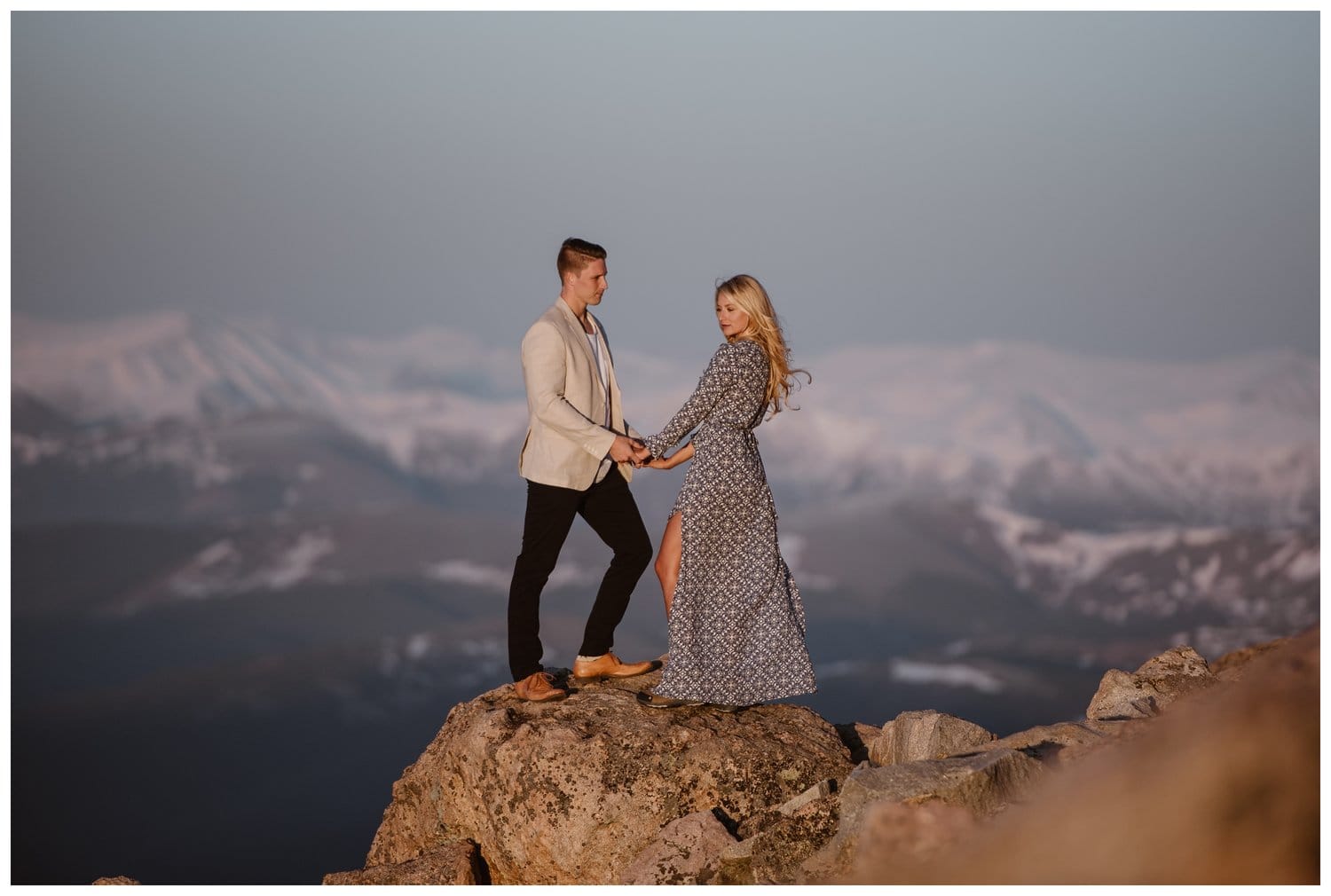 Couple holds hands and stands at the edge of Mt. Evans in Colorado. 