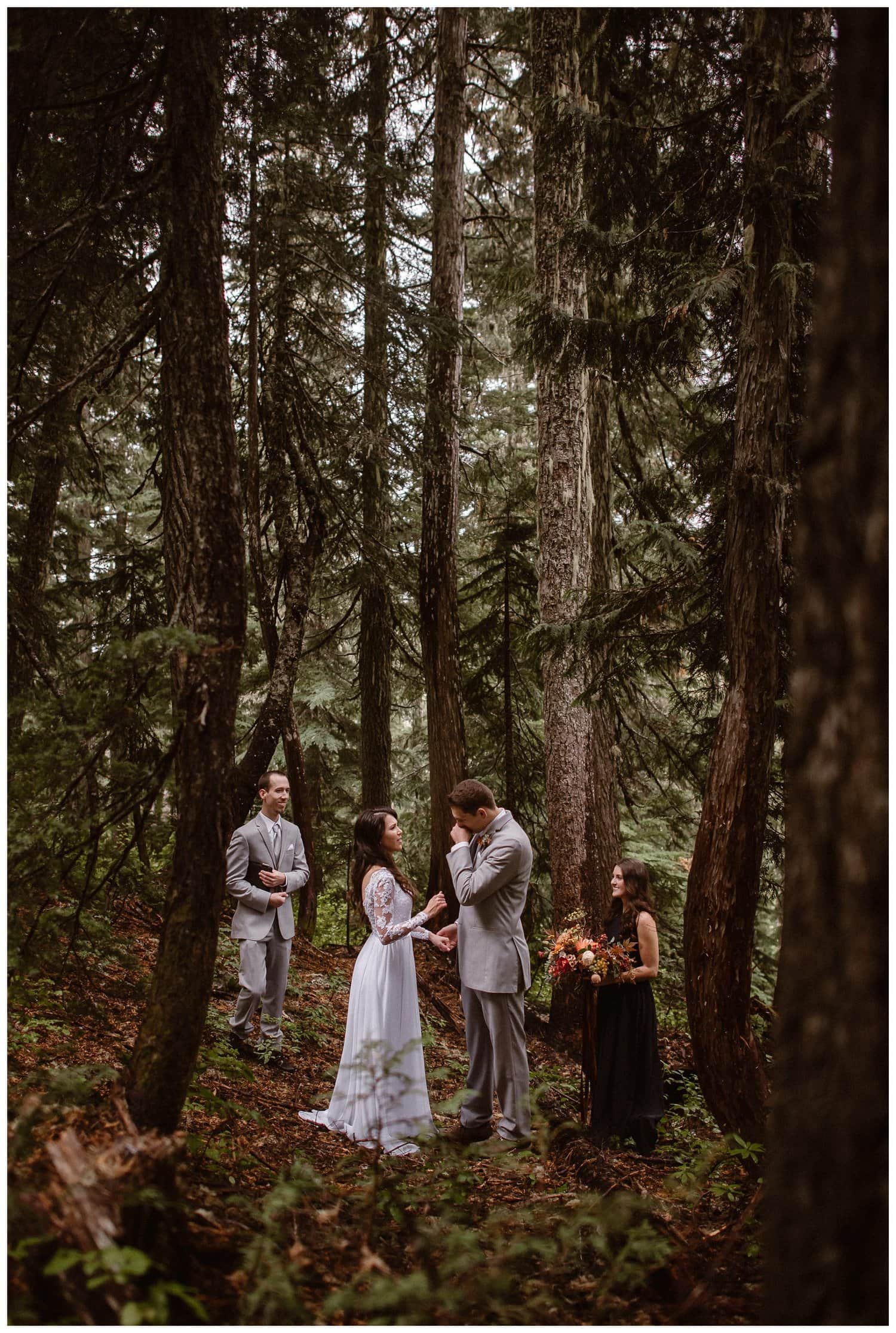 Bride and groom with a man and woman on either side of them during an intimate elopement ceremony in a forest. 