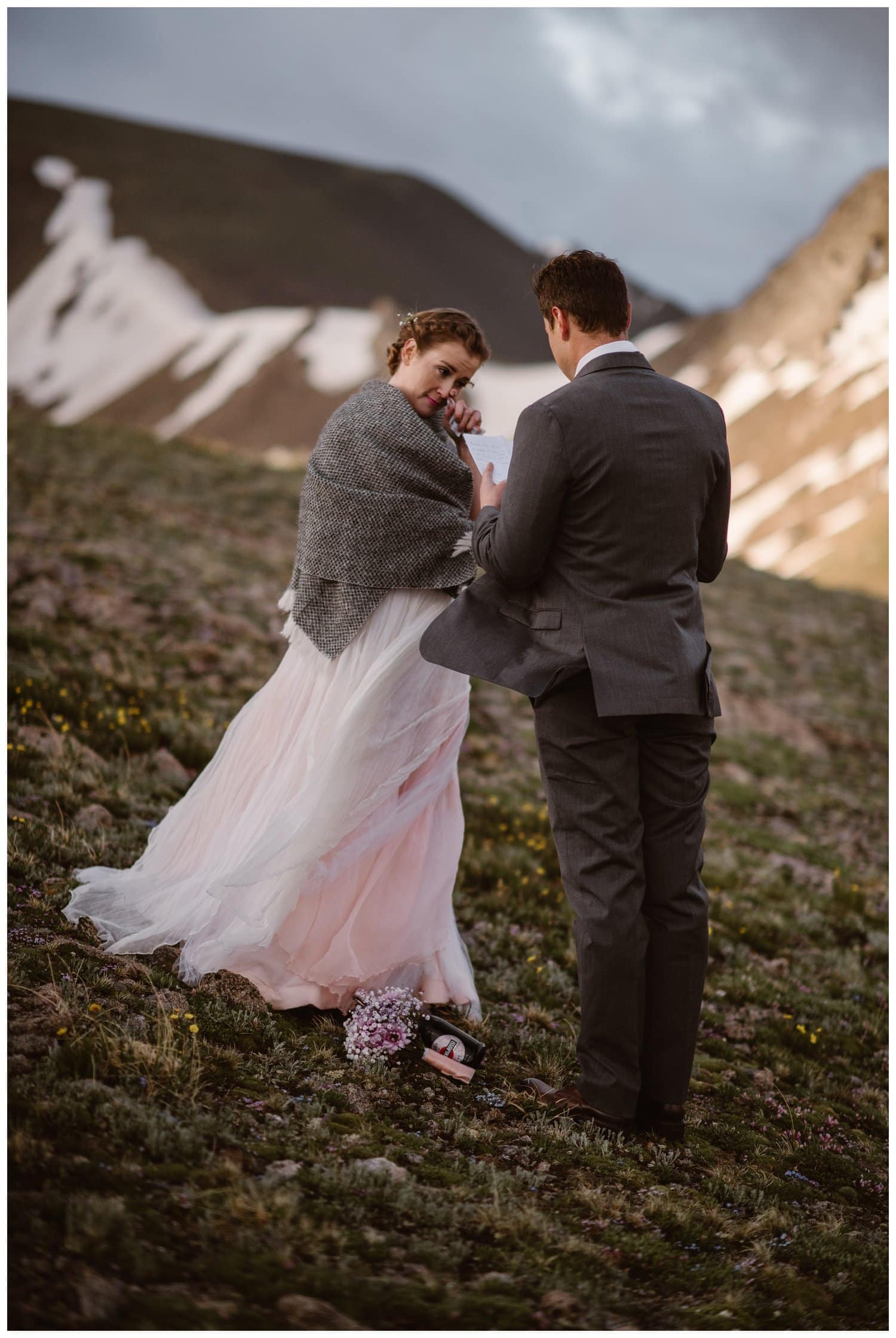 Groom reads his vows as bride wipes away a tear during a sunrise hiking elopement near Aspen, Colorado. 