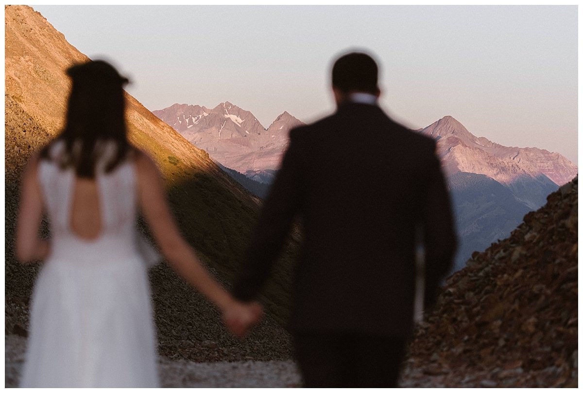 Bride and groom hold hands at Ophir Pass, in Colorado. 