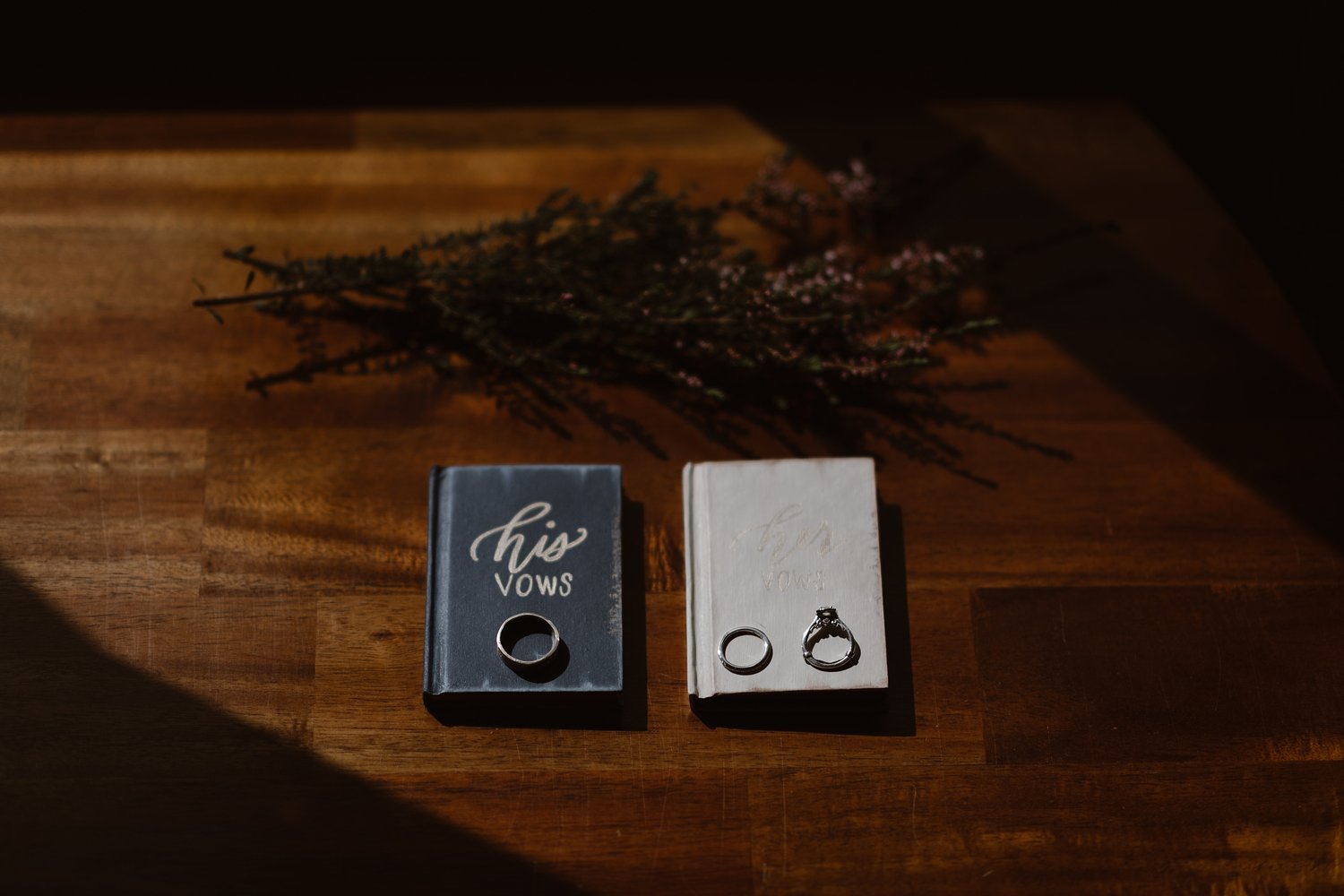 Flat lay of bride and groom's vow books and rings. 