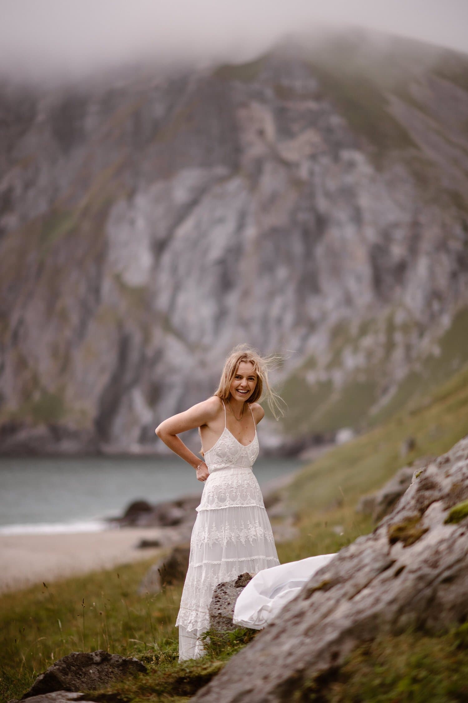 Bride putting on her white, lace wedding dress on a beach on Norway.