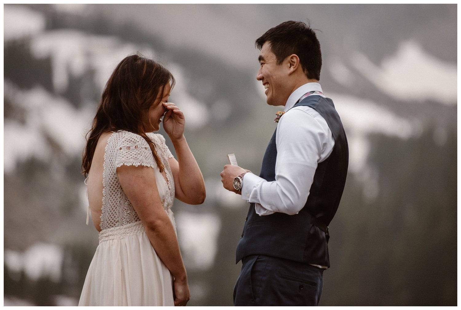 Bride and groom laugh during their intimate elopement ceremony near Boulder, Colorado. . The bride wipes away a tear. 