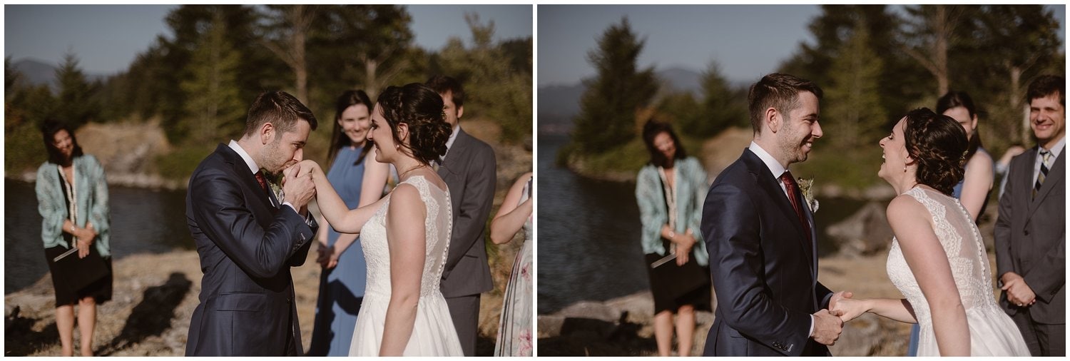 Groom kisses the bride's hands while she smiles at him during their intimate elopement ceremony at the Columbia River Gorge in Oregon.