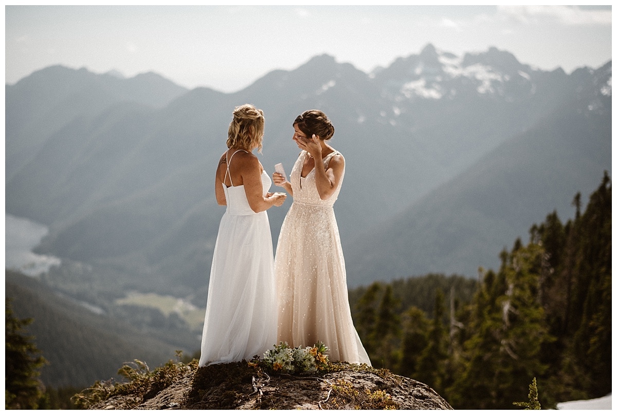 Two brides read their vows during intimate elopement ceremony on a glacial mountain in Tofino, Canada. 