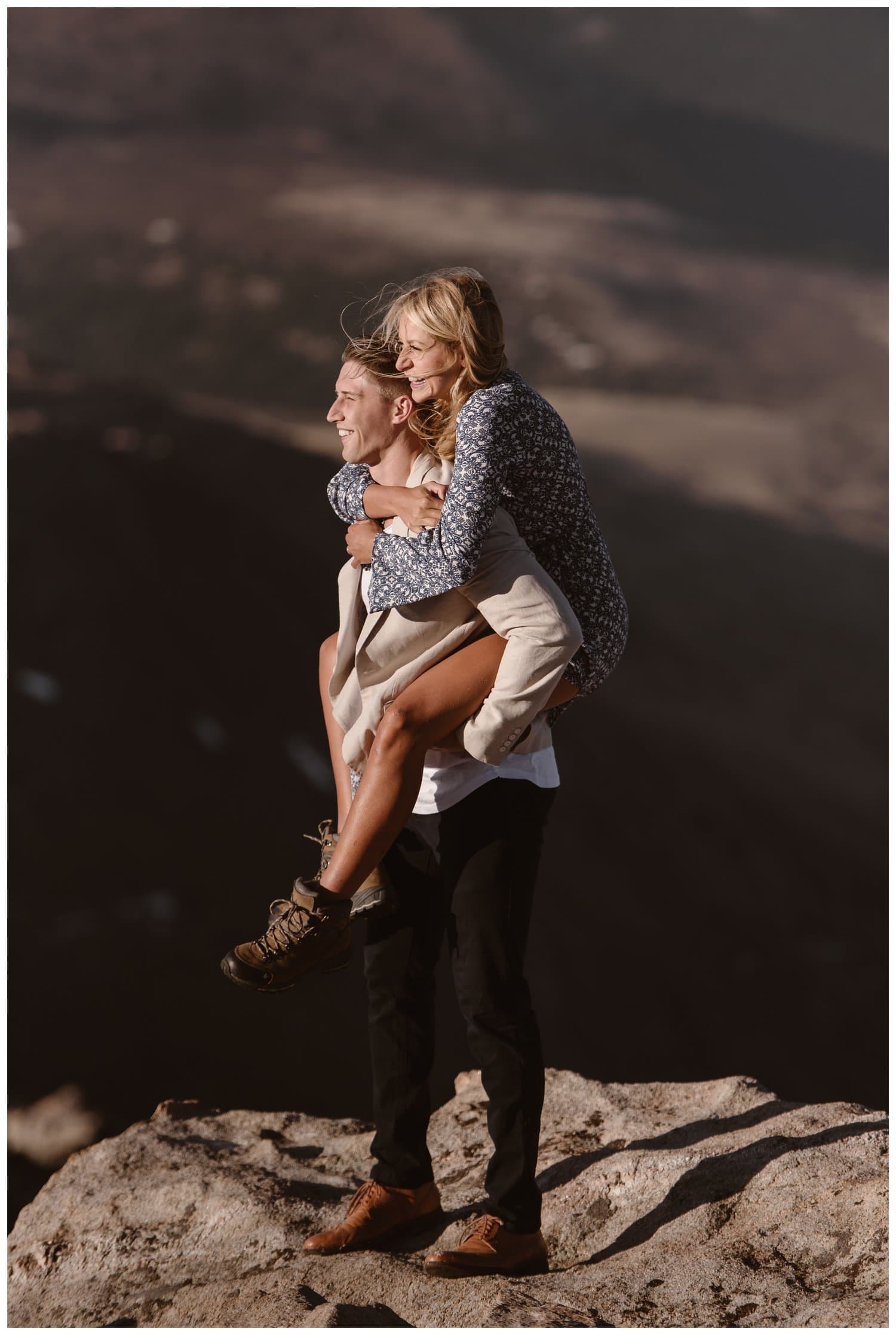 Man gives woman a piggyback ride at the top of Mt. Evans in Colorado. 