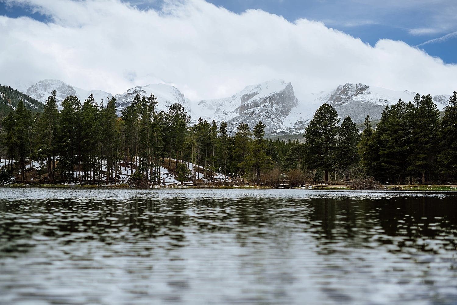 Landscape of Sprague Lake, with forest and snow-capped peaks in the background, at Rocky Mountain National Park, Colorado. 