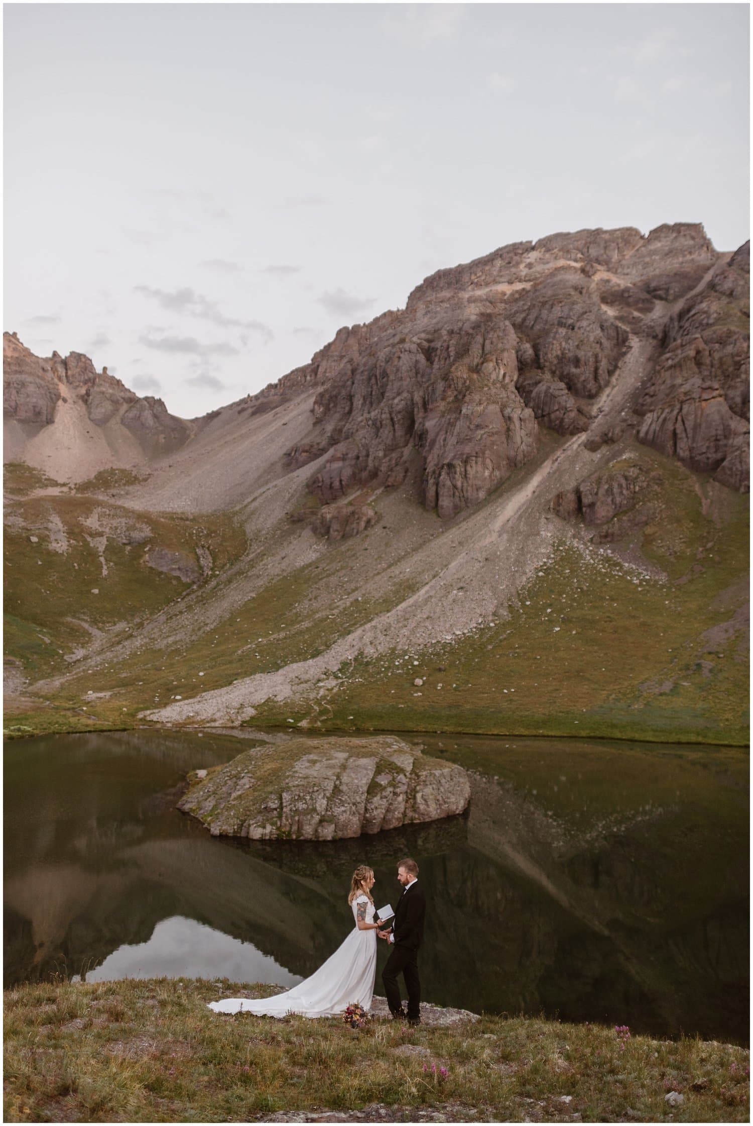 Bride and groom say their vows in front of alpine lake in Ouray, Colorado. 