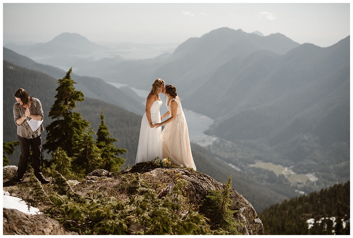 Two brides kiss during intimate elopement ceremony on glacial mountain in Tofino, Canada. 