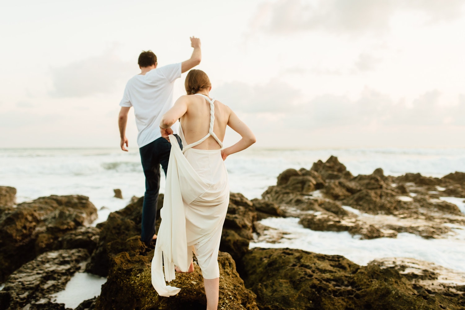 Bride and groom walk across rocks together along the shore in Santa Teresa, Costa Rica.