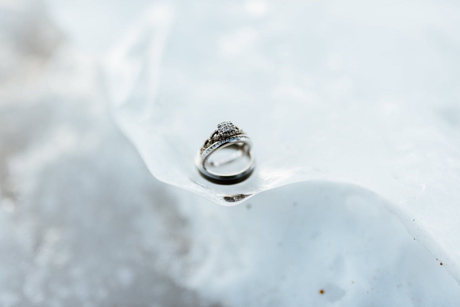 Close-up of bride and groom's rings on ice. 