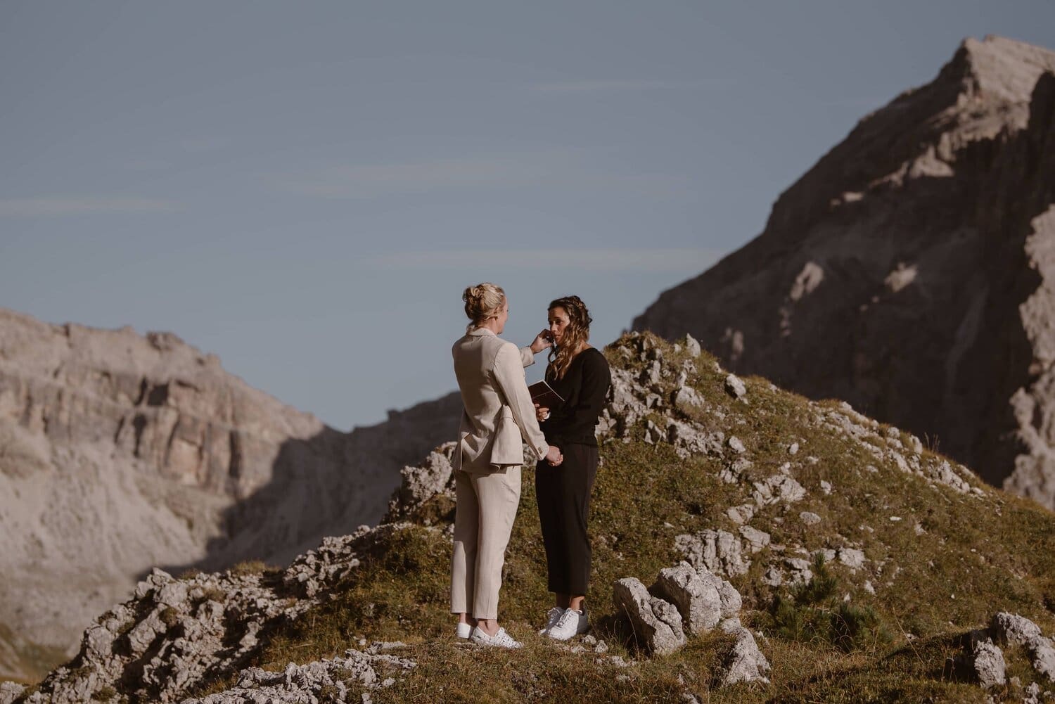 Two brides reading vows during their wedding ceremony in the Italian Dolomites.