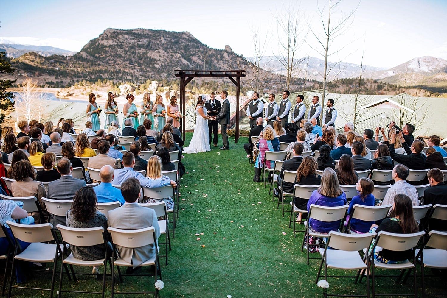 Bride and groom hold hands during their ceremony at Mary's Lake Lodge in Estes Park, Colorado. 