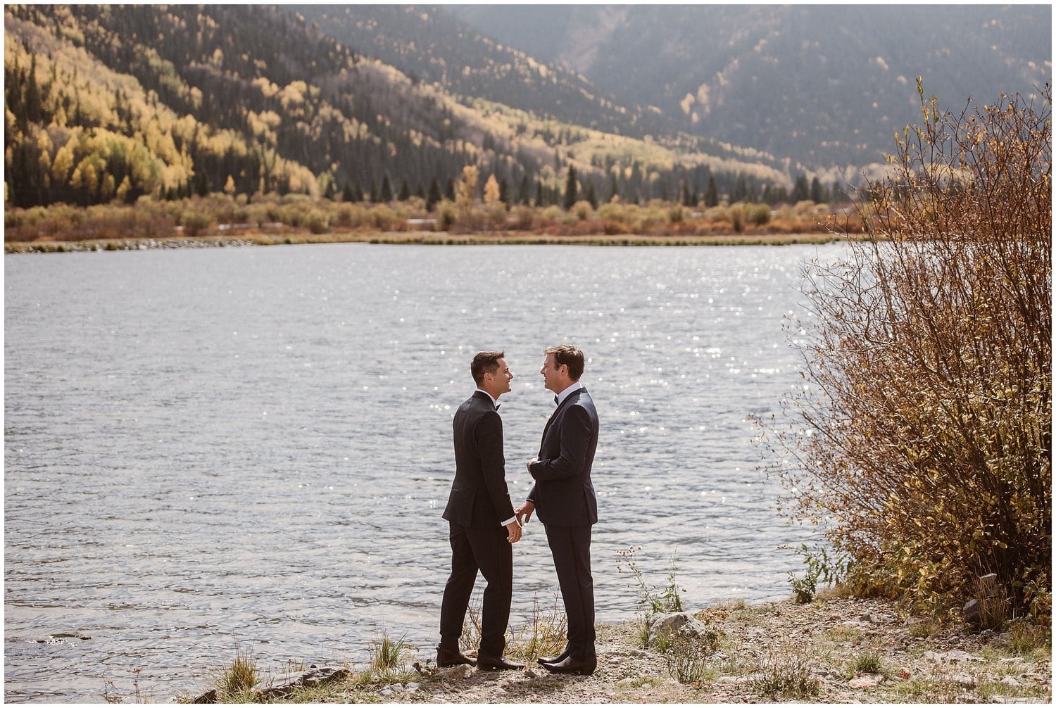 Grooms stand in front of lake and mountains in Ouray, Colorado. 