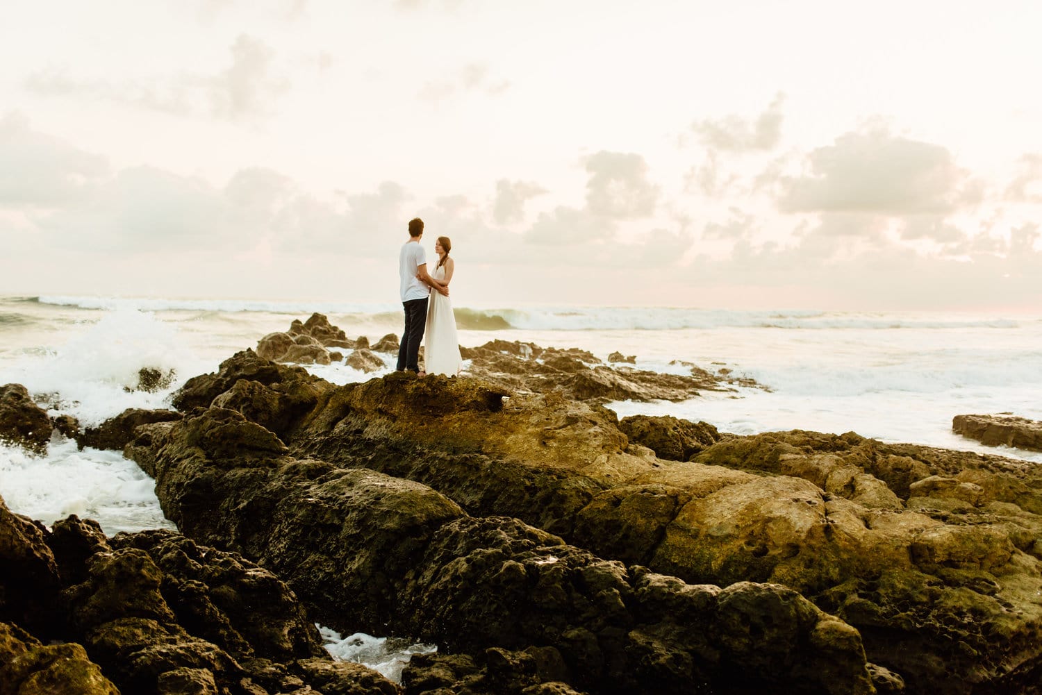 Bride and groom standing on rocks along the shore in Santa Teresa, Costa Rica.