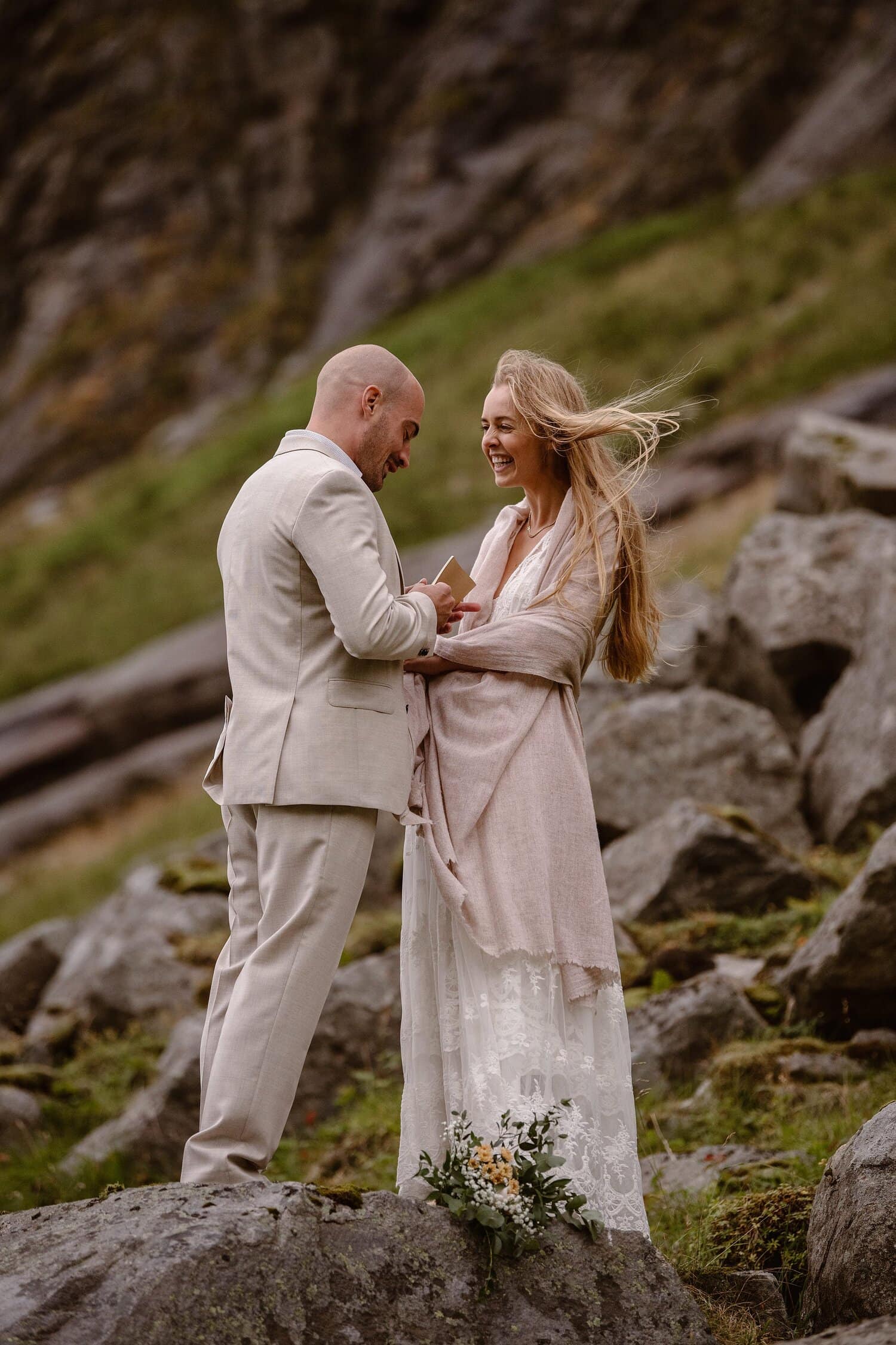 Groom reads his vows during an intimate elopement ceremony on the beach in Norway. The bride and groom are both smiling.