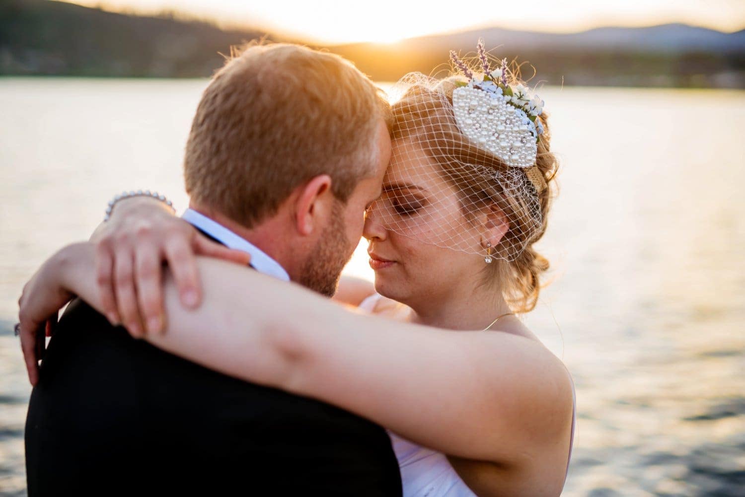 Bride and groom embrace in front of a lake, on their elopement day, in Grand Lake, Colorado. 