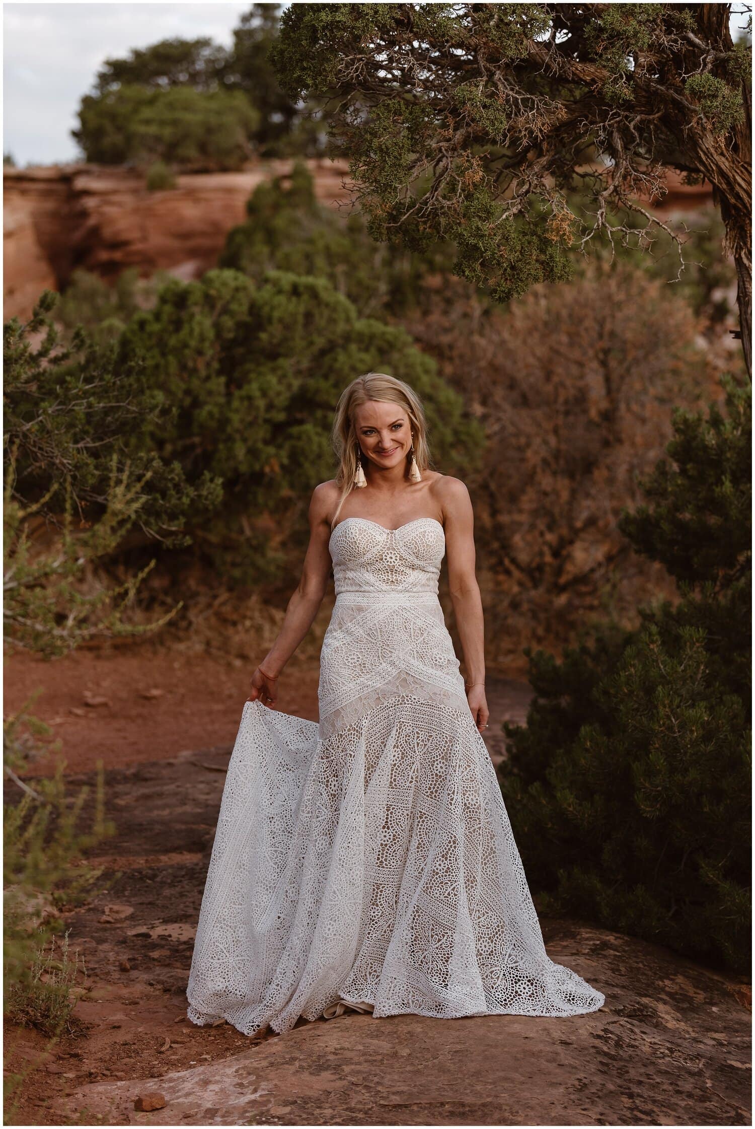 Bride smiles and holds onto her dress at Colorado National Monument. 
