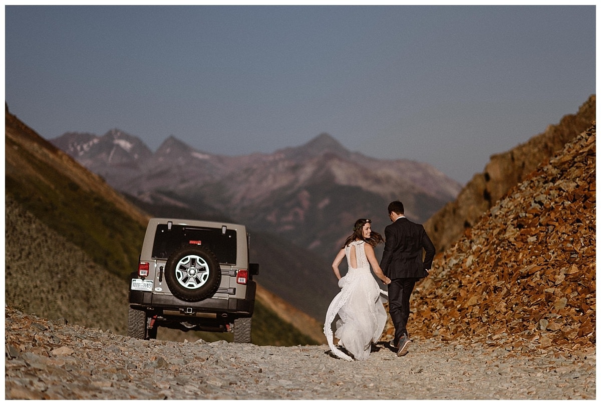 Bride and groom hold hands and walk at Ophir Pass, in Colorado. 
