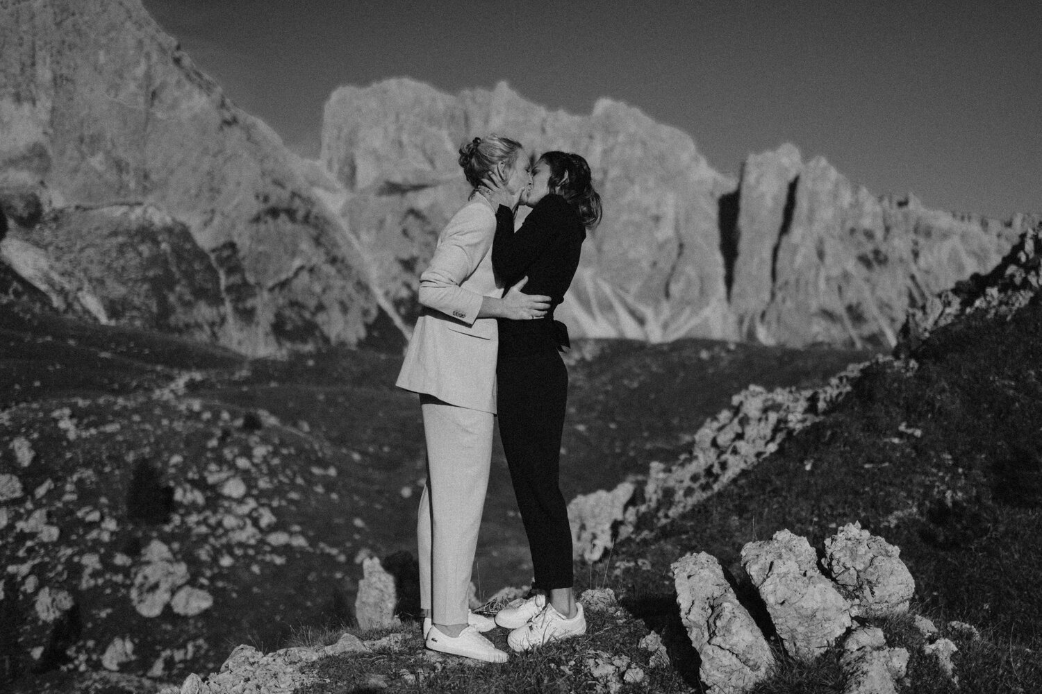 Two brides kissing in the Italian Dolomites. Photo is in black and white.