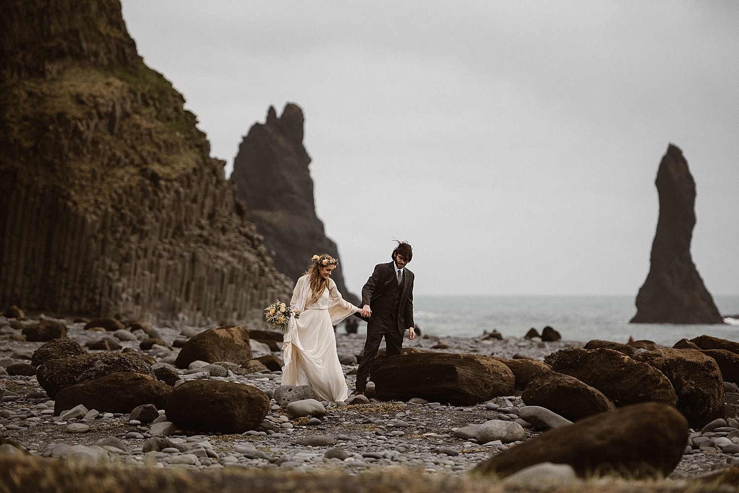 Bride and groom walk along a beach in Iceland. 