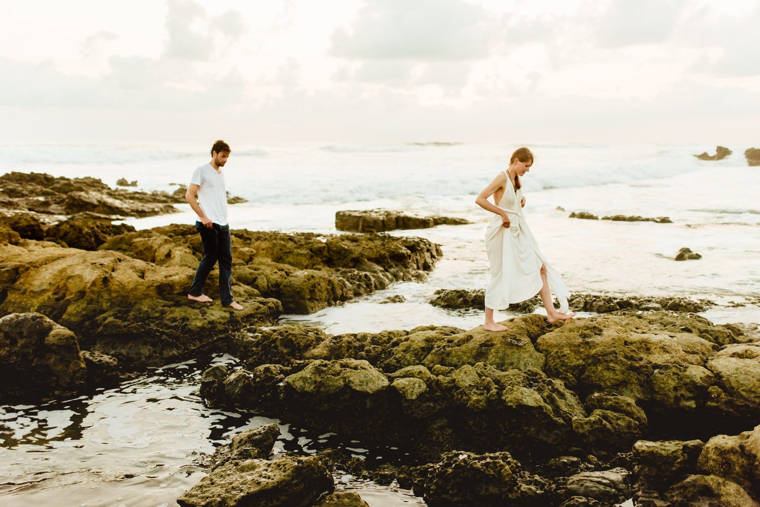 Bride and groom walk on rocks along the shore in Santa Teresa, Costa Rica.