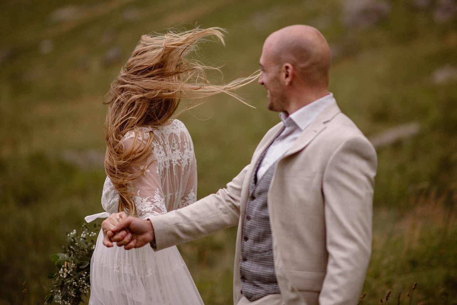 Bride and groom hold hands and walk along a hill on their elopement day in Norway. 