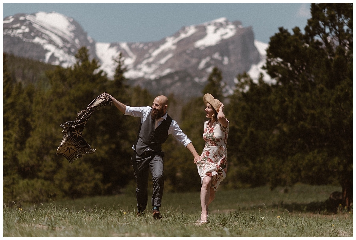 Bride and groom run through a meadow together in Rocky Mountain National Park. 