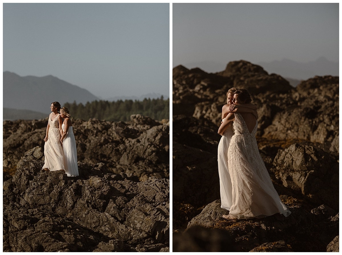 Two brides embrace while standing on rocks along the shore on Shell Island in Tofino, Canada. 