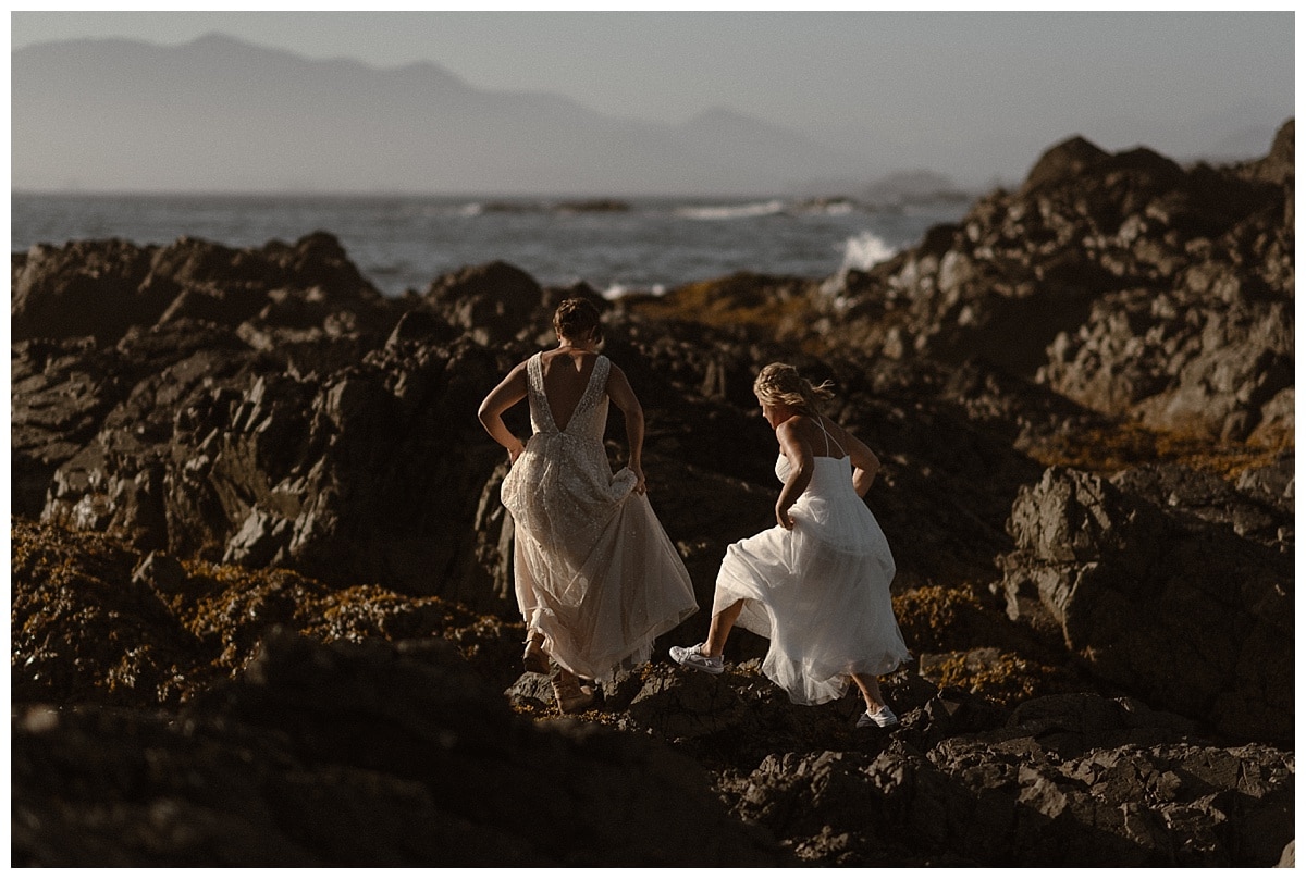 Two brides walk on rocks along the shore on Shell Island in Tofino, Canada. 