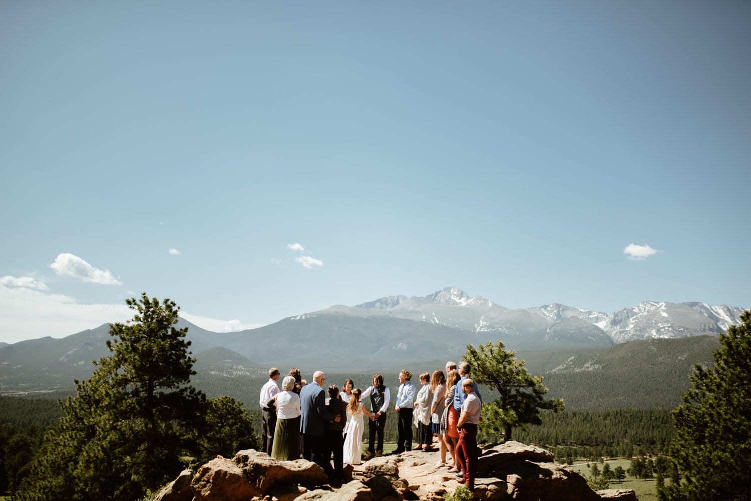 Friends and family gather around bride and groom during intimate elopement ceremony at 3M Curve in Rocky Mountain National Park, Colorado. 