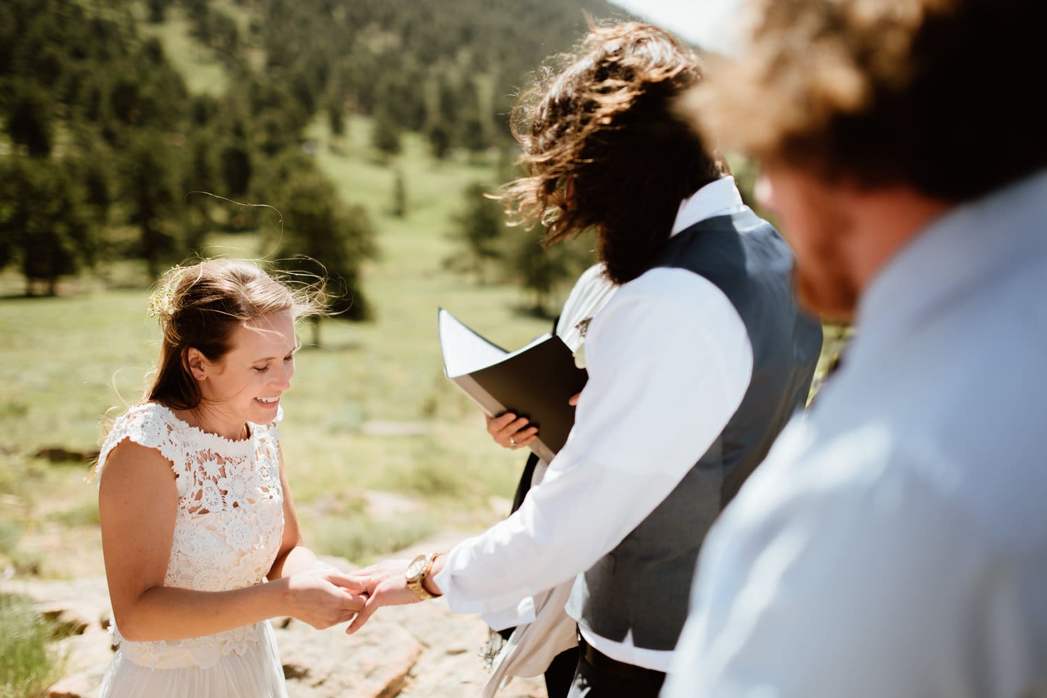 Bride places ring on grooms finger during intimate elopement ceremony at 3M Curve in Rocky Mountain National Park, Colorado. 