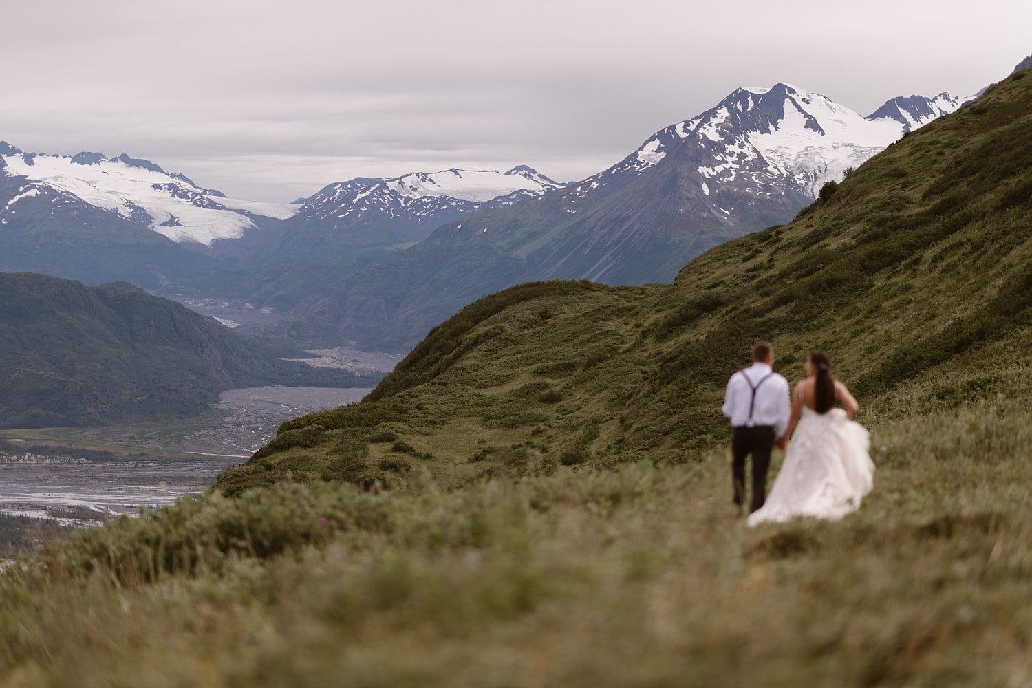 Bride and groom on their elopement day in Alaska. There are snow-capped mountains in the background. 