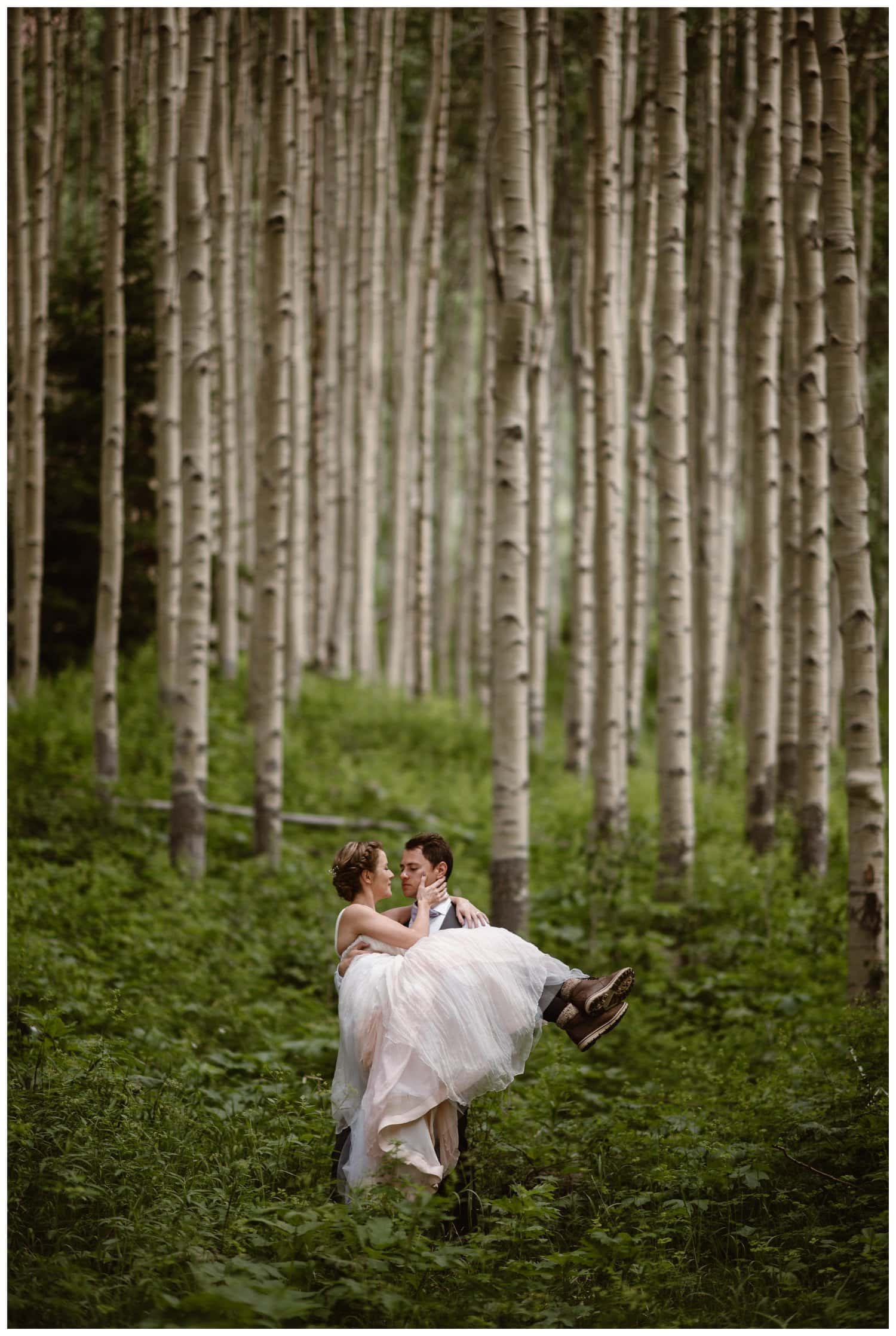 Groom holds bride in an aspen forest near the Maroon Bells, in Colorado. 