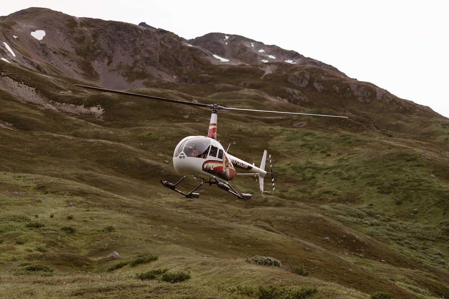 Helicopter landing in Alaska. There are mountains in the background. 