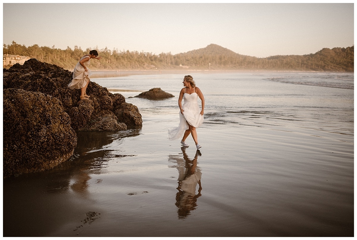Two brides walk along the shore of a beach in Tofino, Canada. 