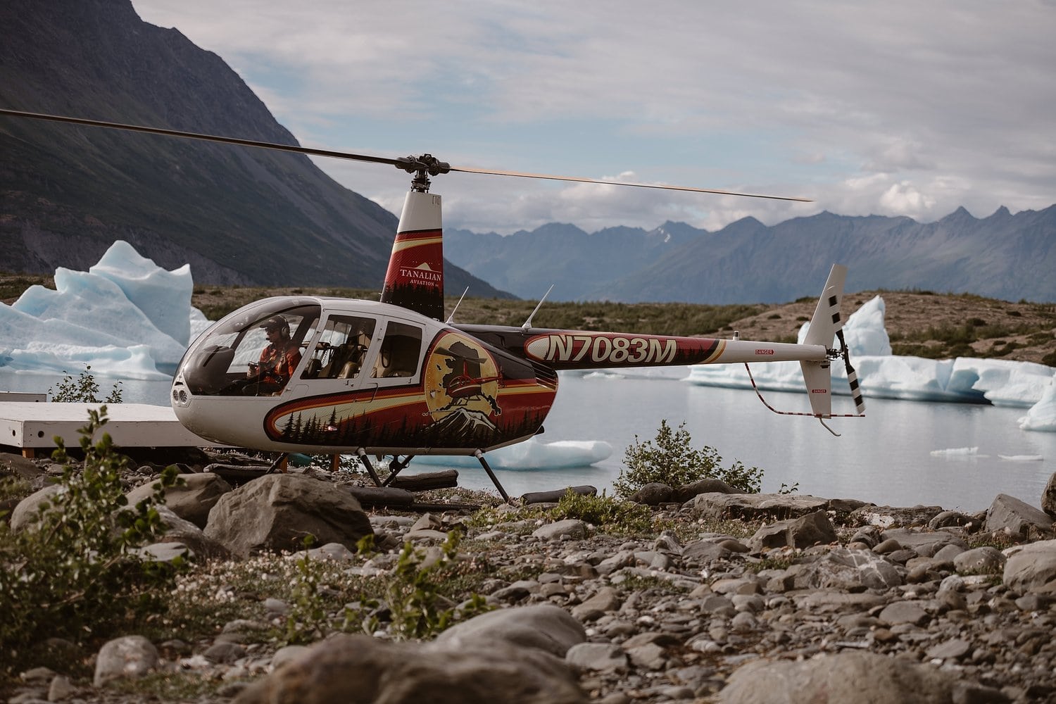 Helicopter on ground, in front of glacial lake in Alaska. 