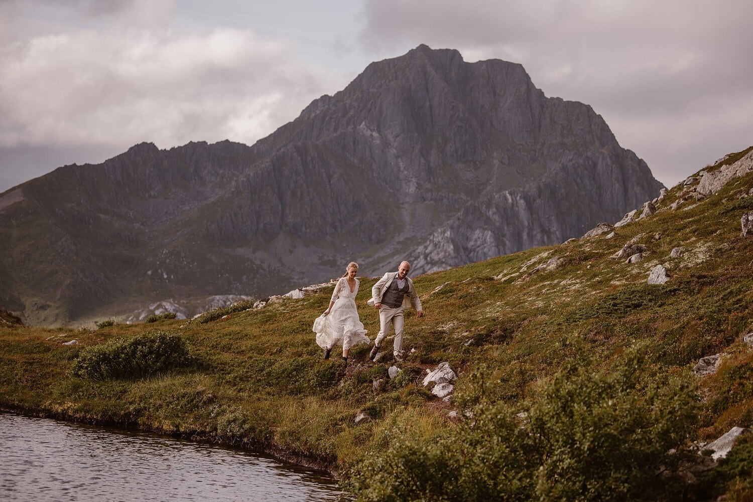Bride and groom hiking next to the water on their elopement day in Norway. 