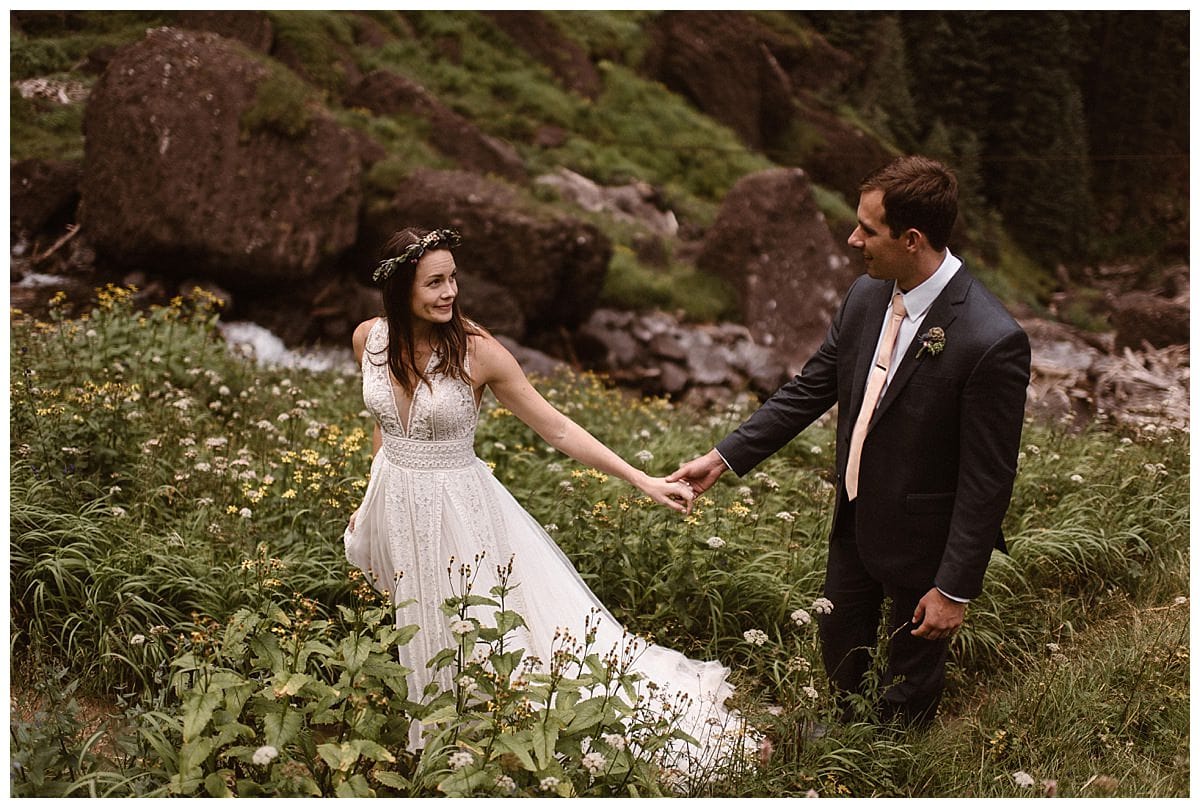 Bride and groom holds hands while smiling at each other at Bridal Veil Falls in Telluride, Colorado. 