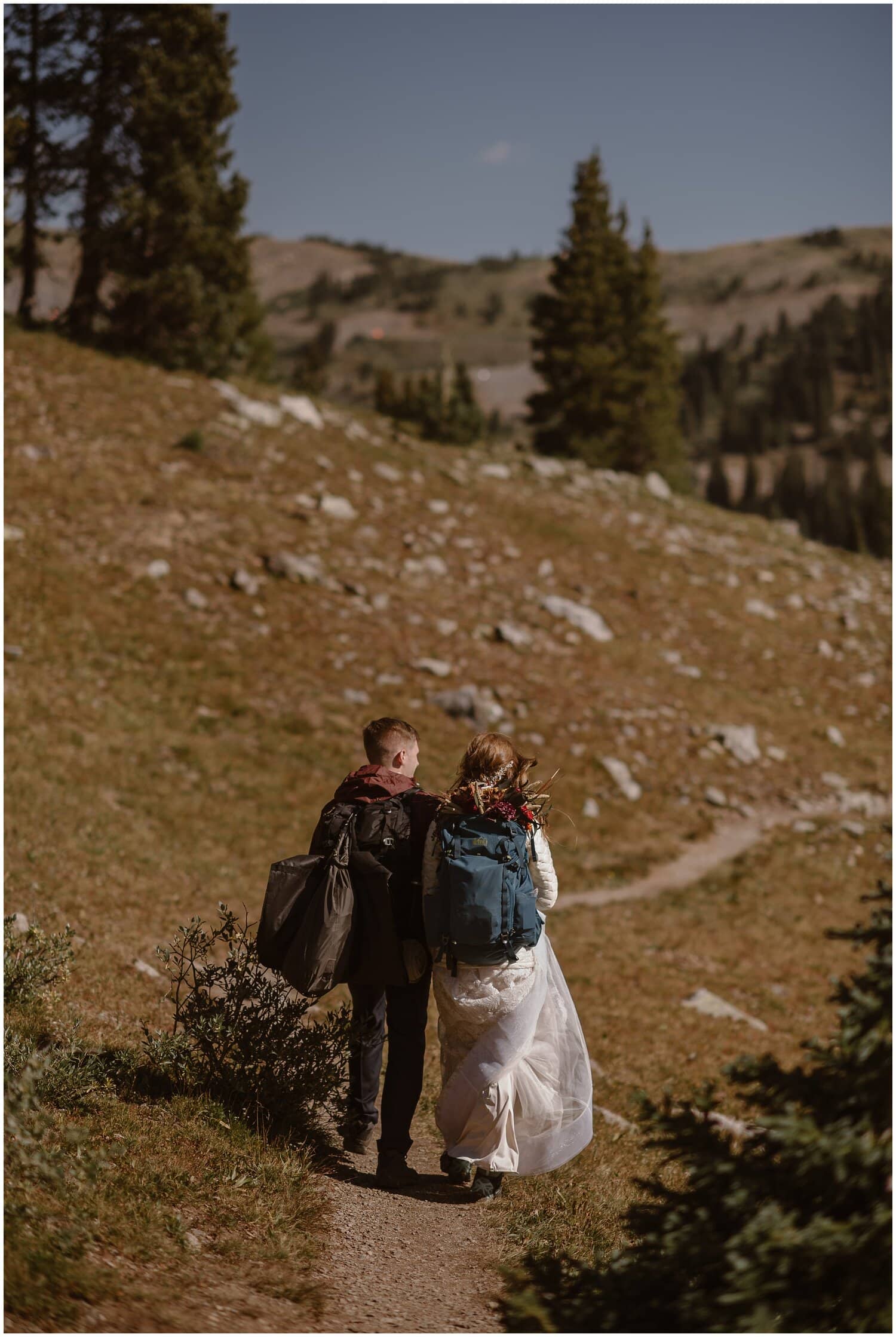 Bride and groom hiking on trail in Buena Vista, Colorado. Mountains and trees in background. 